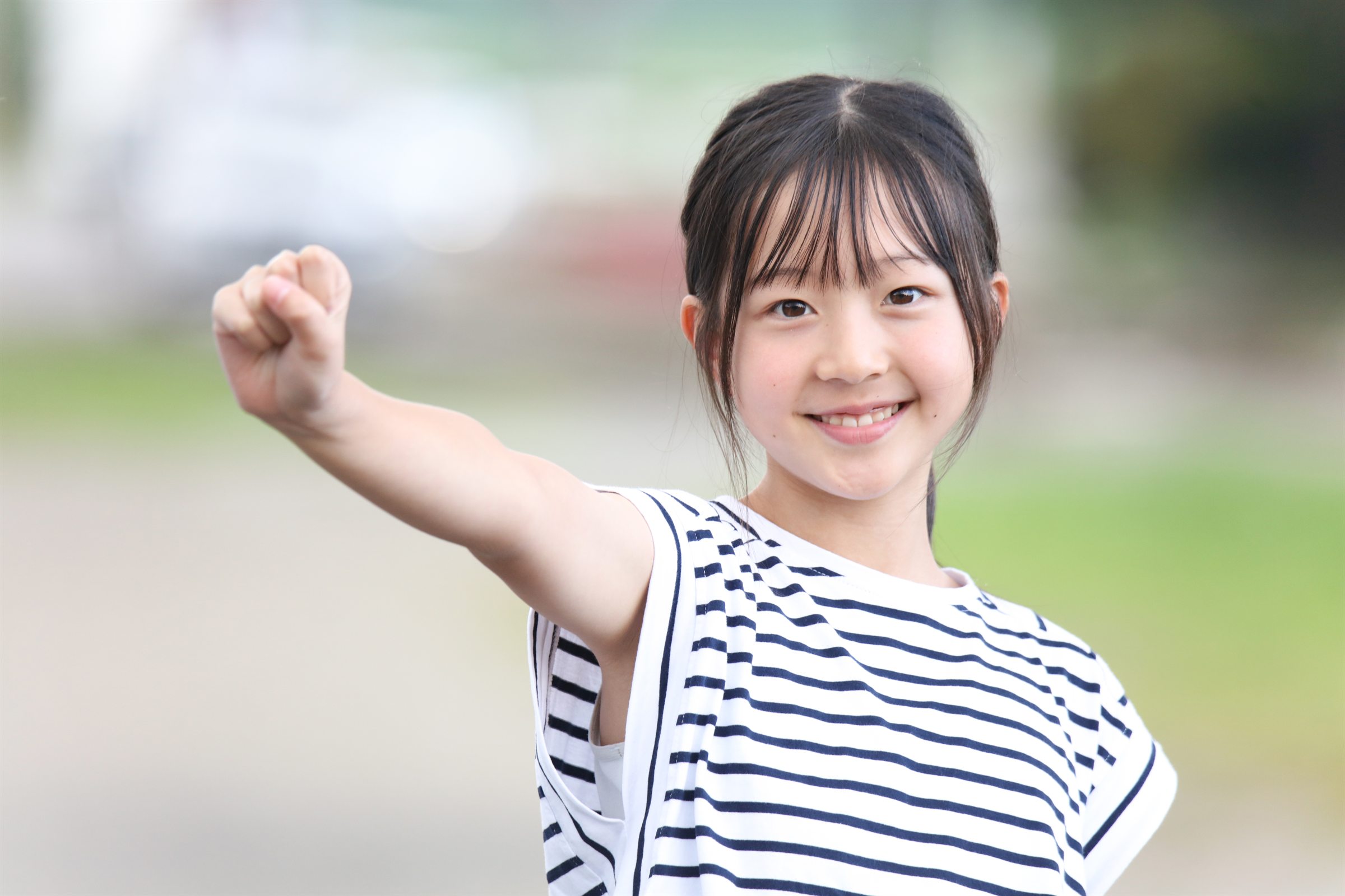 屋外で元気なポーズを見せる子ども