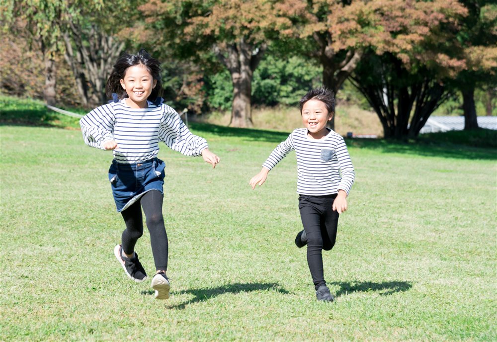芝生の広場を笑顔で走る子どもたち